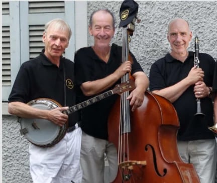 Three musicians in black shirts posing with a banjo, upright bass, and clarinet against a gray wall