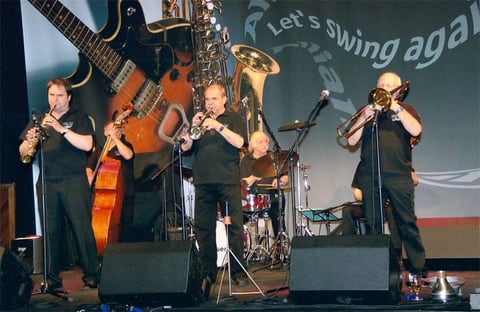 Jazz musicians performing on stage with instruments including saxophone, cello, and trumpet